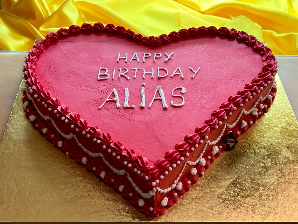 Torta a cuore rosa con scritta di auguri