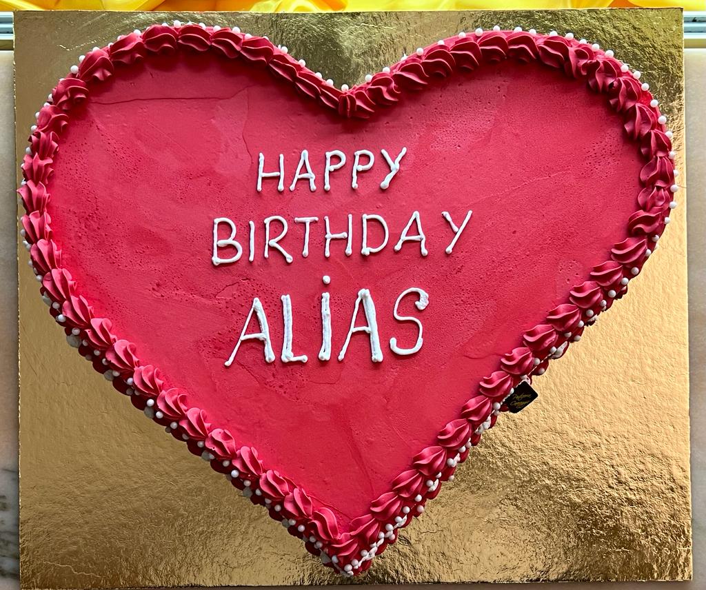 Torta a cuore rosso con scritta di auguri