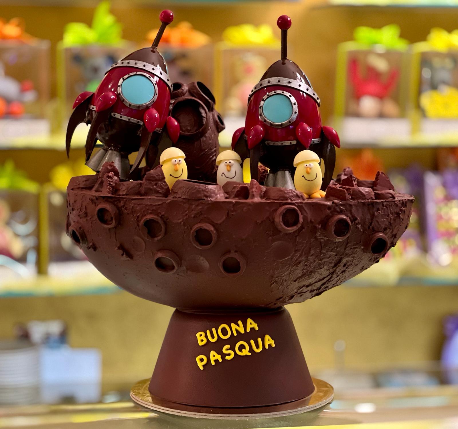 Uovo di cioccolato a forma di astronavi sulla luna con scritta Buona Pasqua, pasticceria Caravaggio 2024