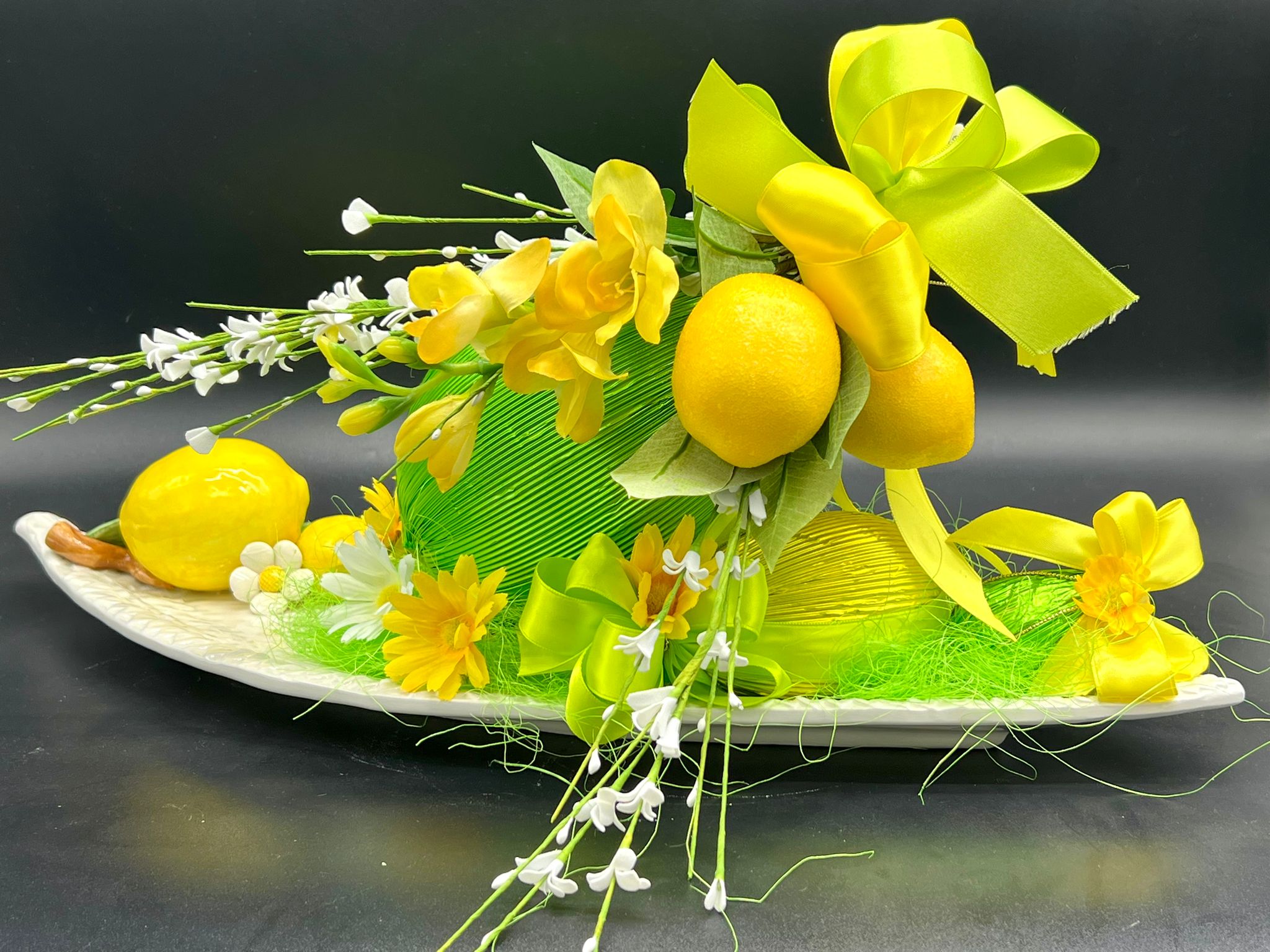 Composizione decorativa ovale con limoni e fiori gialli, pasticceria Caravaggio Pasqua 2024
