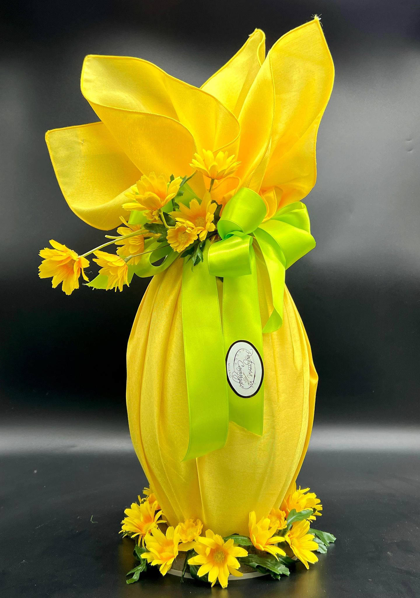 Uovo di cioccolato fasciato in tessuto giallo con fiori decorativi, pasticceria Caravaggio Pasqua 2024
