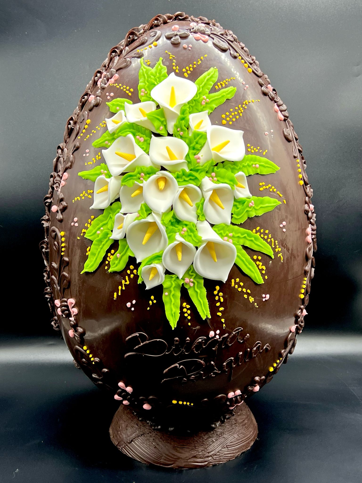Uovo di cioccolato fondente decorato con calle bianche e scritta Buona Pasqua, pasticceria Caravaggio 2025