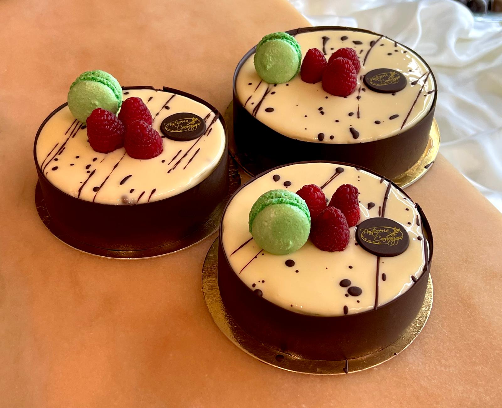 Tre torte natalizie con glassa bianca, lamponi freschi e macaron al pistacchio