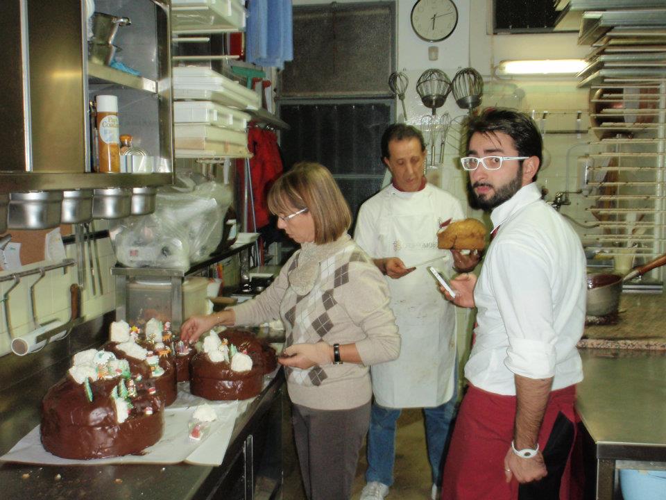 Pasticceri decorano tronchetti al cioccolato con villaggio innevato in zucchero