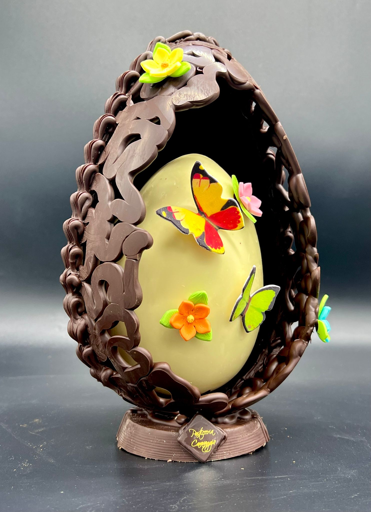 Dettaglio dell'uovo di cioccolato decorato con farfalle e fiori in un nido intrecciato