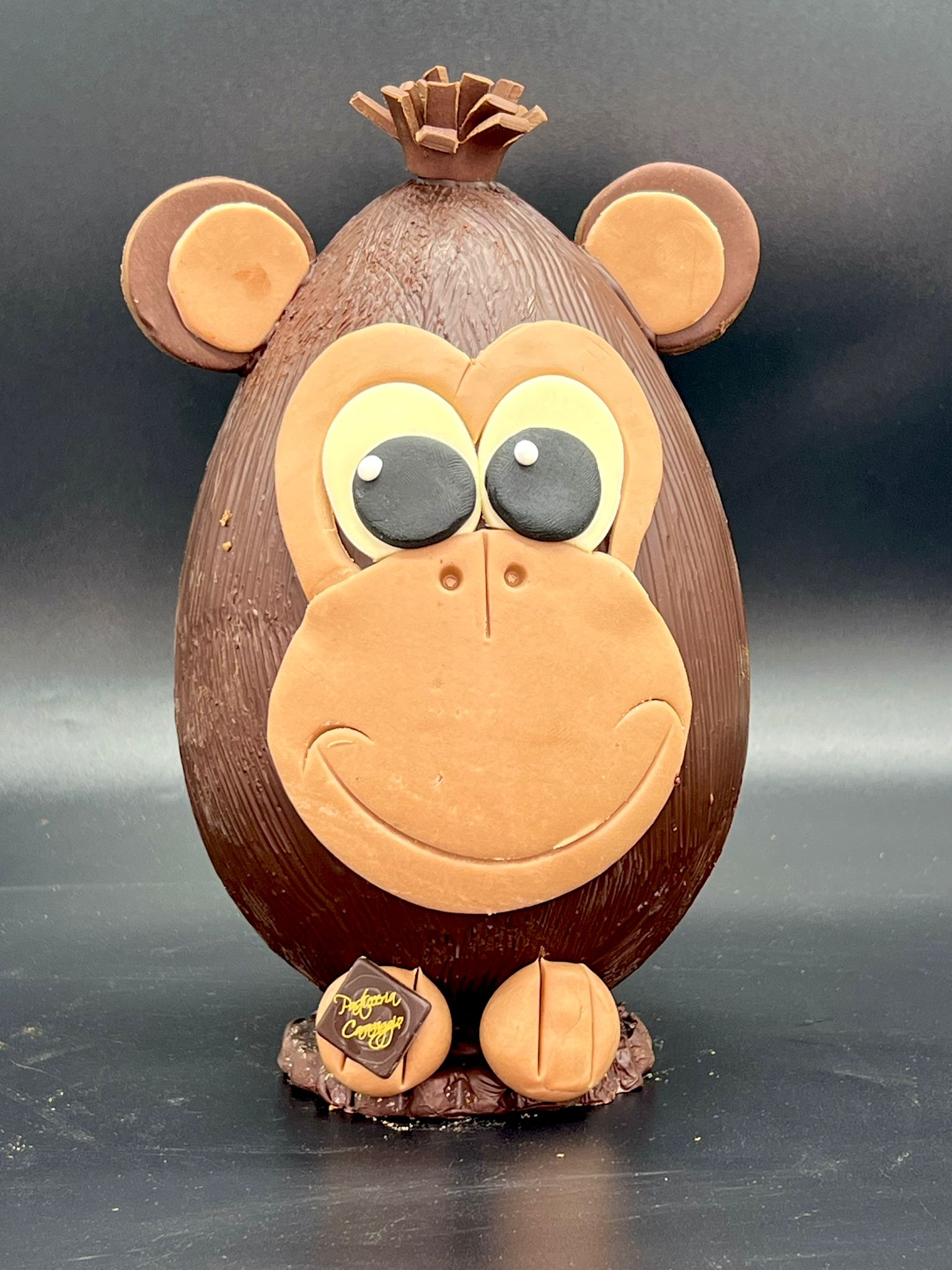 Uovo di cioccolato a forma di scimmietta sorridente con ciuffo e occhioni