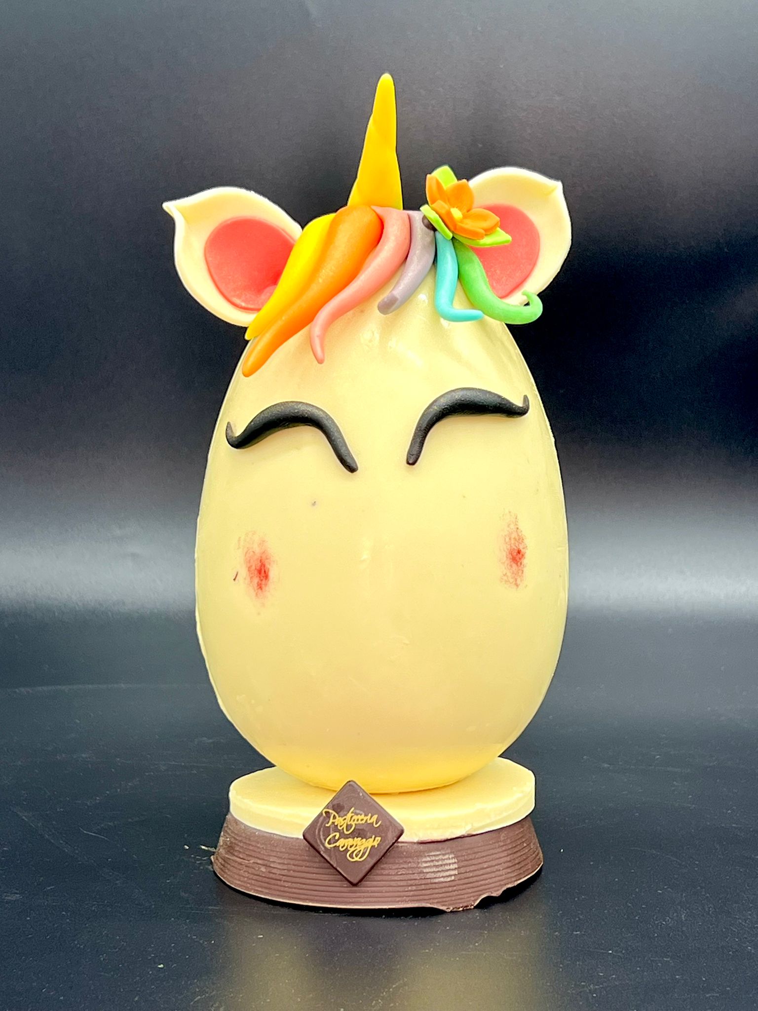 Uovo di cioccolato a forma di unicorno con criniera arcobaleno e corno dorato